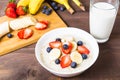 Oatmeal with fruits and glass of milk on wooden table