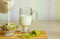 Oatmeal in a glass bowl, sliced kiwi lies next to it. Milk is poured from the bottle. Selective focus, place for text.