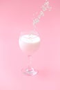an oatmeal granule is poured into a glass of milk. pink background. Royalty Free Stock Photo