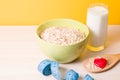 oatmeal in a green bowl and a wooden large spoon with oatmeal and a small red happy heart on a wooden table