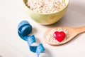 oatmeal in a green bowl and a wooden large spoon with oatmeal and a small red happy heart