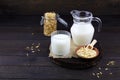 Oatmeal milk in a jug and a glass, oats in a jar, oatmeal flakes in a bowl on a dark wooden background. Vegetable milk Royalty Free Stock Photo