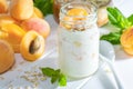 Oatmeal milkshake, smoothie or yogurt with fresh apricot on a white wooden table