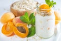 Oatmeal milkshake, smoothie or yogurt with fresh apricot on a white wooden table