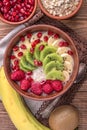 Oatmeal porridge with banana, kiwi fruit , raspberries and garnet for healthy breakfast.