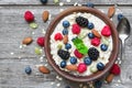 Oatmeal porridge with berries and nuts in a bowl with a spoon for healthy breakfast on rustic wooden background