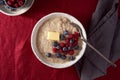 Oatmeal porridge with blueberry, bilberry on dark red cranberry linen tablecloth.