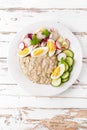 Oatmeal porridge with boiled egg and vegetable salad with fresh radish, cucumber and lettuce. Healthy dietary breakfast Royalty Free Stock Photo