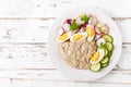 Oatmeal porridge with boiled egg and vegetable salad with fresh radish, cucumber and lettuce. Healthy dietary breakfast Royalty Free Stock Photo