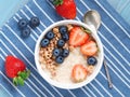 Oatmeal porridge with fresh strawberry, blueberry, granola on blue background. Healthy breakfast. Top view, close-up Royalty Free Stock Photo