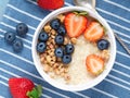 Oatmeal porridge with fresh strawberry, blueberry, granola on blue background. Healthy breakfast. Top view, close-up Royalty Free Stock Photo