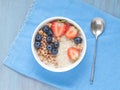 Oatmeal porridge with fresh strawberry, blueberry, granola on blue background. Healthy breakfast. Top view. Royalty Free Stock Photo