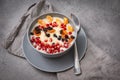 Oatmeal porridge with fruit slices, tangerine slices, raisins, dried apricots, pomegranate seeds on a gray background, healthy