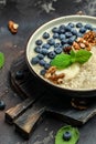 Oatmeal porridge with ripe blueberries, nuts and honey healthy breakfast on rustic wooden background. close up Royalty Free Stock Photo