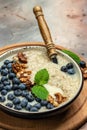 Oatmeal porridge with ripe blueberries, nuts and honey healthy breakfast on rustic wooden background. close up Royalty Free Stock Photo