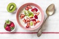 Oatmeal porridge with slices of kiwi, strawberries, almonds in pink bowl, spoon on white tablecloth Top view Flat lay Vegan food Royalty Free Stock Photo