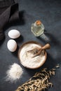 Oatmeal in a wooden bowl with eggs and oli on a dark background. Natural organic flour for home baking