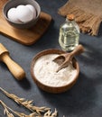 Oatmeal in a wooden bowl with eggs, rolling pin and oli on a dark background. Natural organic flour for home baking