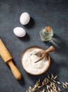 Oatmeal in a wooden bowl with eggs, rolling pin and oli on a dark background. Natural organic flour for home baking