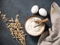 Oatmeal in a wooden bowl with a scoop on a dark blue background with eggs and dry branches oats. Organic ingredients for baking. Royalty Free Stock Photo