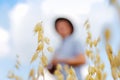 Oats field. Harvester. Blurred farmer standing in gold wheat field with blue sky in background. Young man wearing Royalty Free Stock Photo