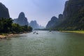 Oats with tourists cruising in the Li River with the tall limestone peaks in the background near Yangshuo in China