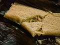 A Oaxacan style mexican tamale broken open to display chicken filling, cooked in banana leaf. Mexican food, travel in Mexico