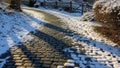 Obblestone pathway partially covered in snow curving through Royalty Free Stock Photo