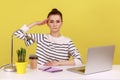 Obedient responsible woman office manager sitting at workplace with laptop and saluting.