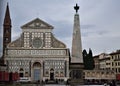 Obelisk with Santa Maria Novella facade and bell tower, in the sky made gray by the clouds in late pomegggio, in Florence.