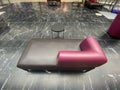 View on lilac brown empty chaiselongue with small round table in rest area of shopping mall