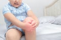 Obese boy suffering from knee pain and sit on bed,