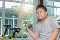 Obese fat boy Lifting dumbbell in fitness room,