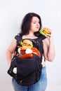 Obese fat young woman with a great backpack full of junk food on Royalty Free Stock Photo