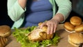 Obese lady tearing pieces of meat off roast chicken junk food digestive disorder