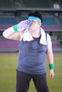 Obese male drinking in the stadium