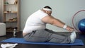 Obese male stretching on mat after home workout, muscle tone, body flexibility