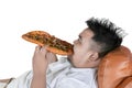 Obese man eating big pizza on the sofa