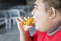 Obese man eating tasty crunchy fried chicken