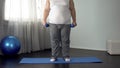 Obese man lifting dumbbells on mat at home, desire to lose weight, fitness