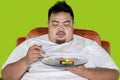 Obese man looks hesitate to eat salad on studio