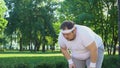 Obese man running in city park, overcoming laziness and insecurity, persistent