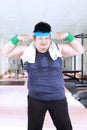 Obese man showing strong arms at the gym