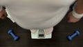 Obese man standing on gym scale, checking weight, slimming training, dieting Royalty Free Stock Photo