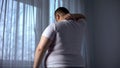 Obese man stretching neck muscles, back pain problems caused by overweight