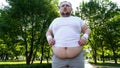 Obese person hardly doing exercises in city park, personal training program