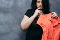 Obese shy woman hesitating to wear vibrant shirt