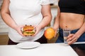 Obese woman with burger and dietitian with fruits Royalty Free Stock Photo