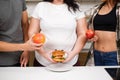 Obese woman with burger and fit people with fruits Royalty Free Stock Photo