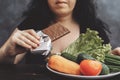 Obese woman eating chocolate refusing healthy food